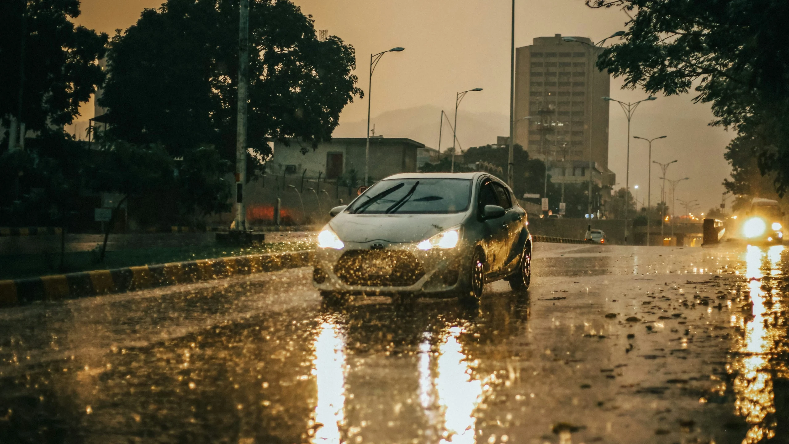 Carro estacionado sob chuva forte com proteção.