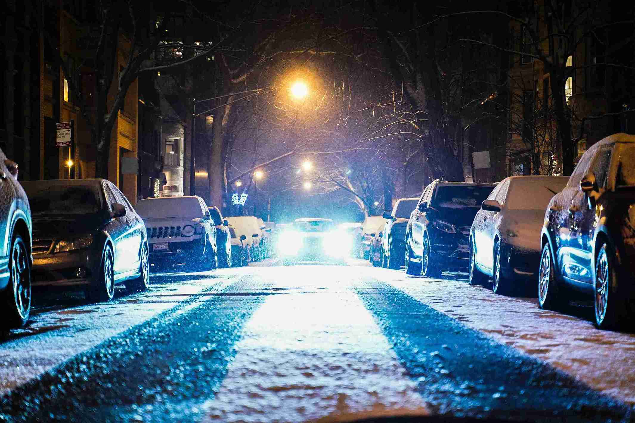 Carro com faróis acesos à noite em uma estrada.