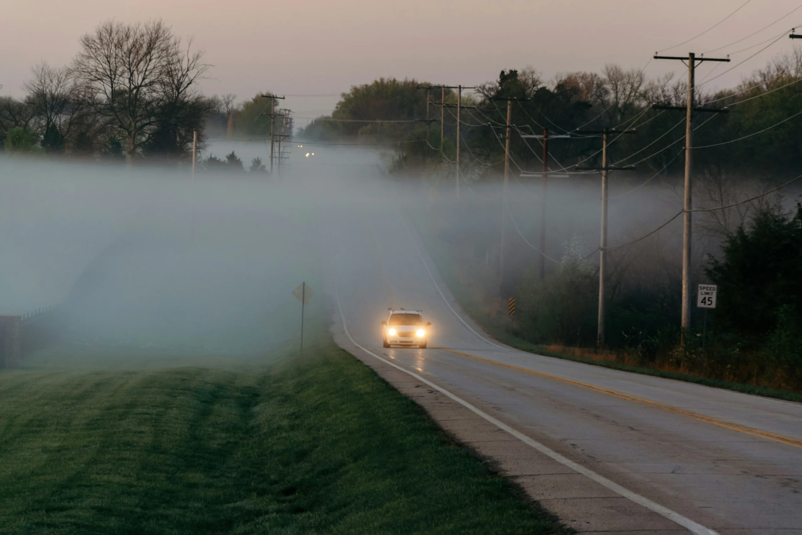 Carro dirigindo em estrada com neblina densa.
