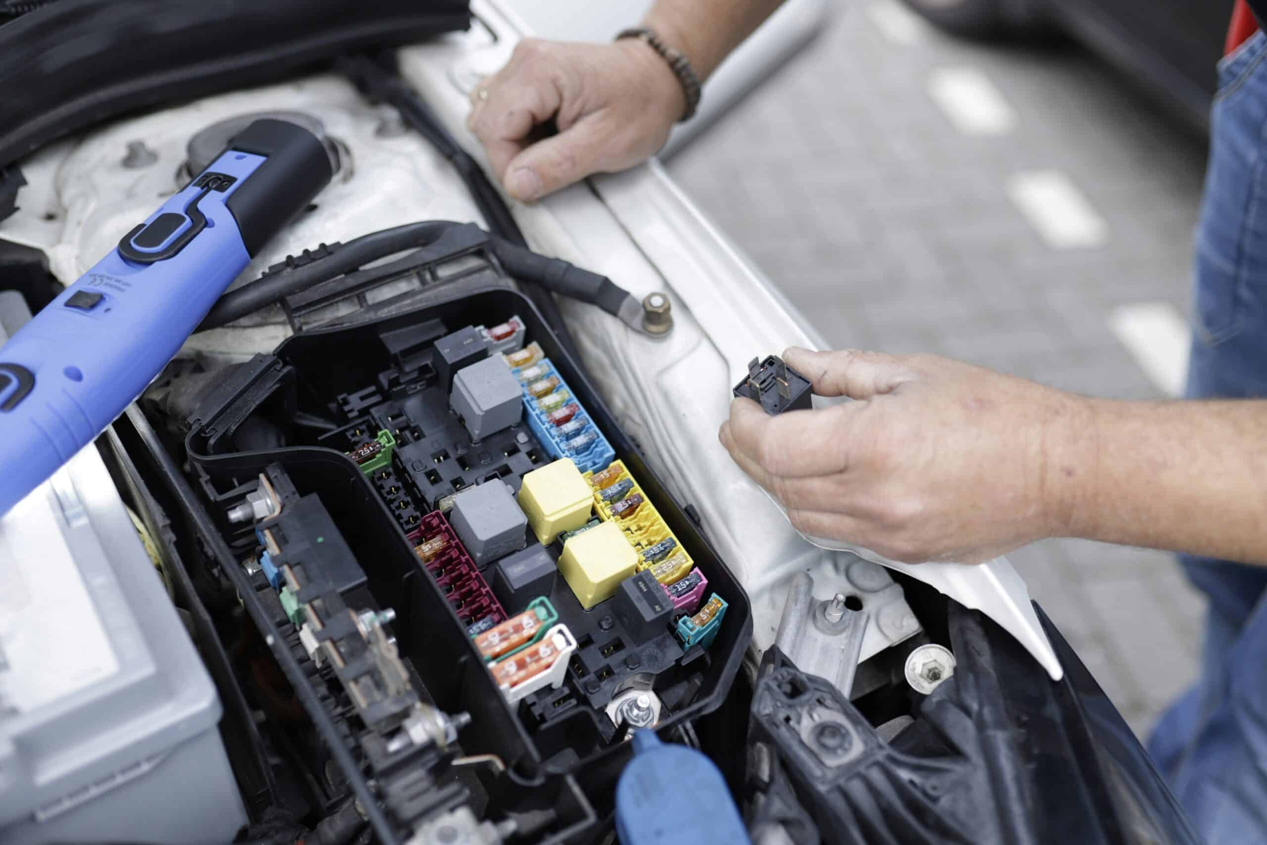 Bateria de carro sendo verificada com capô aberto.