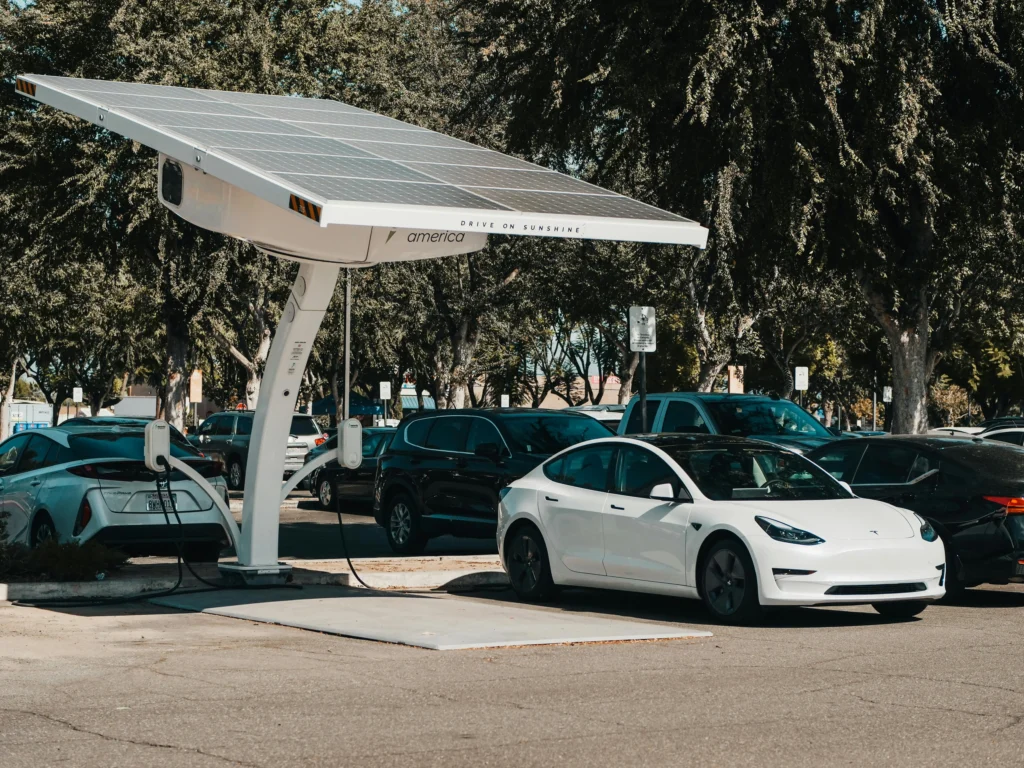 Carro elétrico branco sendo carregado em estação com energia solar em estacionamento urbano