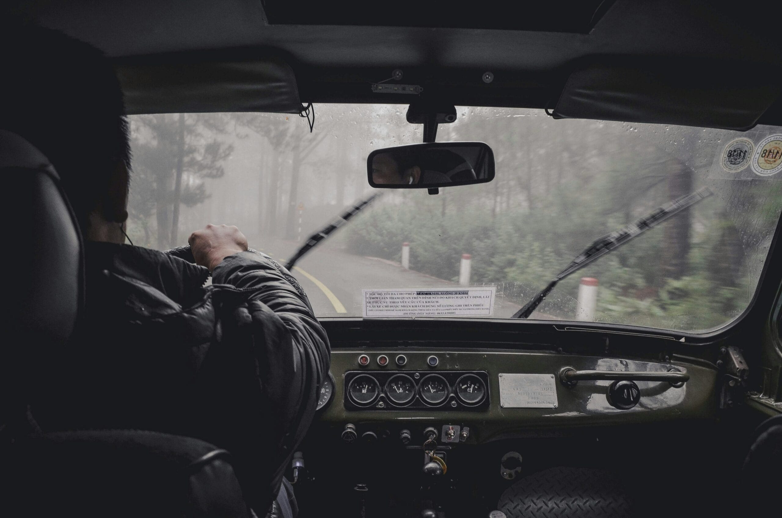Carro dirigindo na chuva com limpadores de para-brisa ligados.