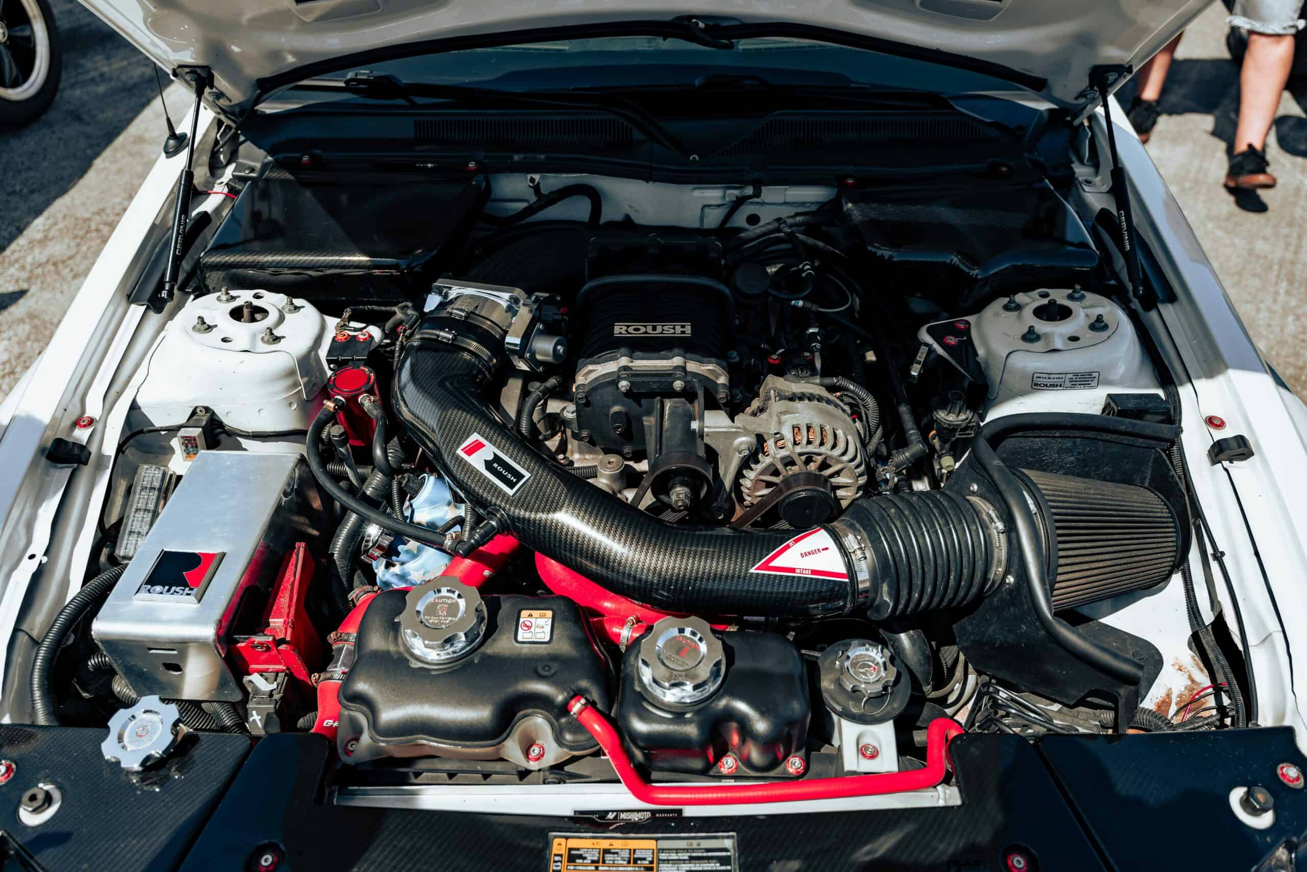 Carro com capô aberto e vapor saindo do motor por superaquecimento.
